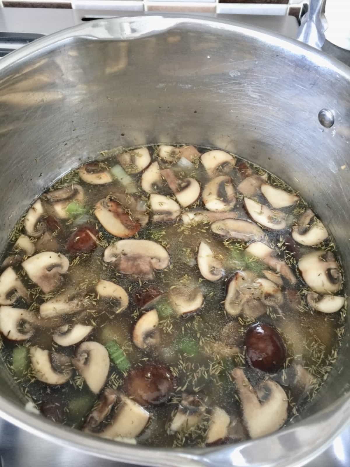 Sliced mushrooms simmering in a pot.