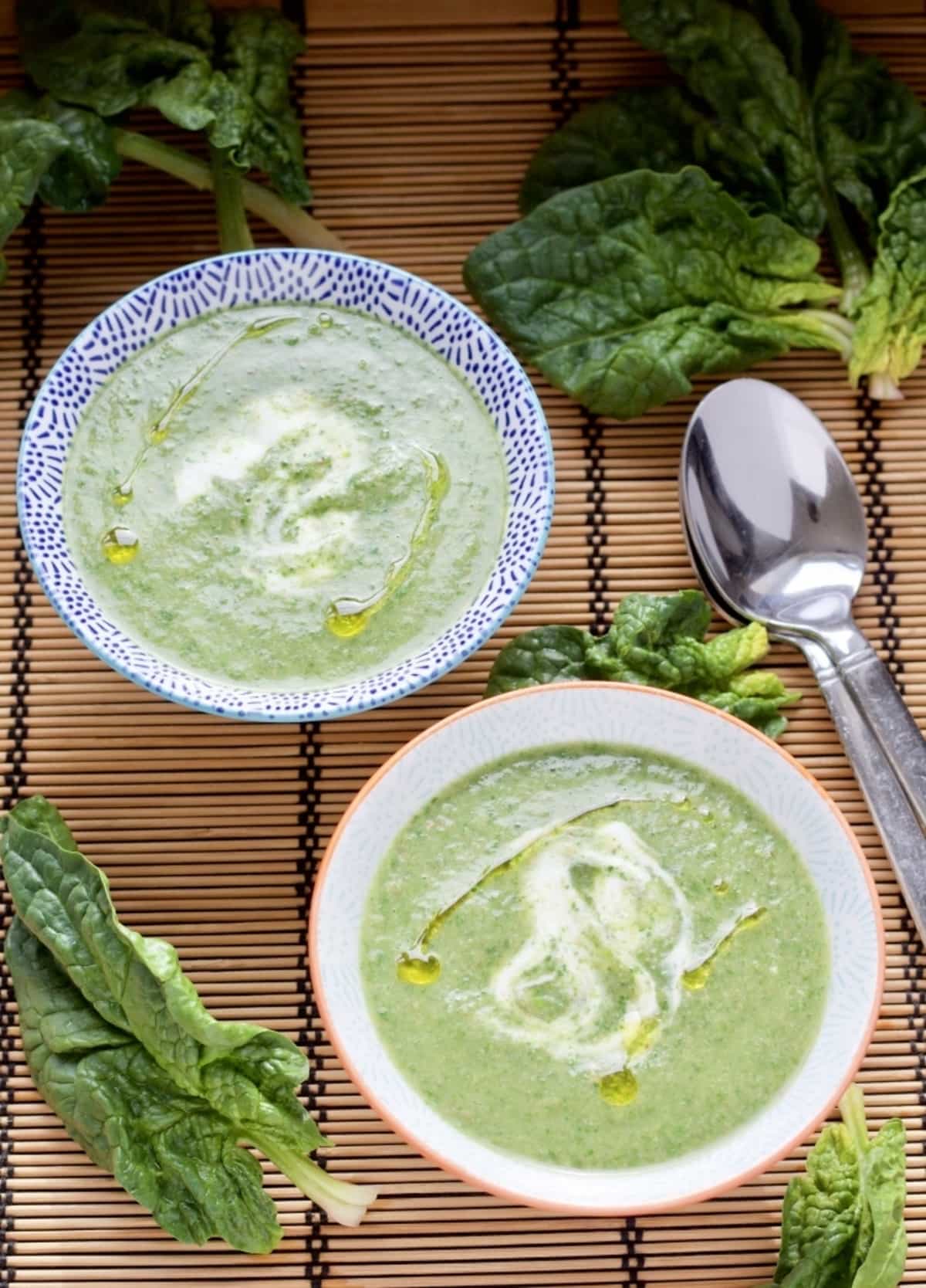 Two bowls of Spinach and Mushroom Soup with two spoons.