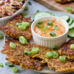 Close up of vegan vegetable fritters surrounding bowl with sauce.