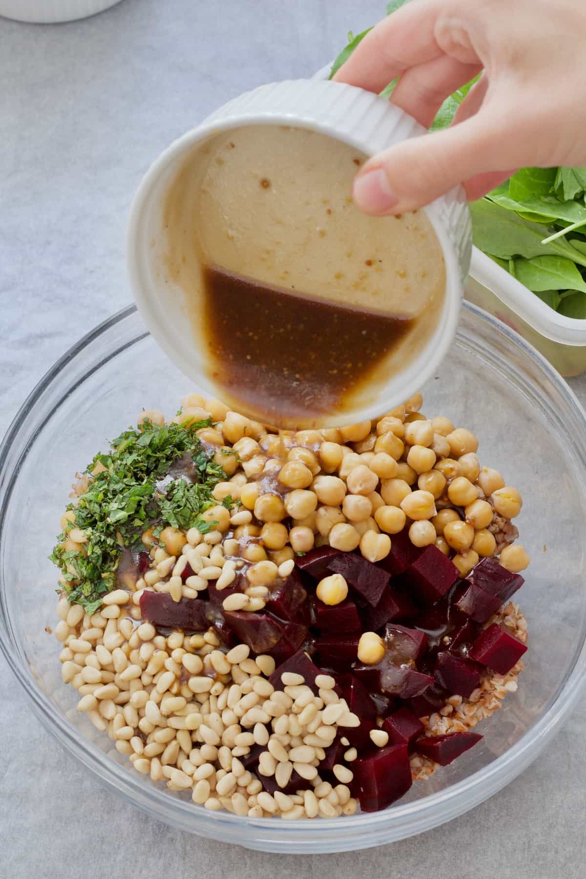 Dressing being poured onto salad ingredients in a bowl.