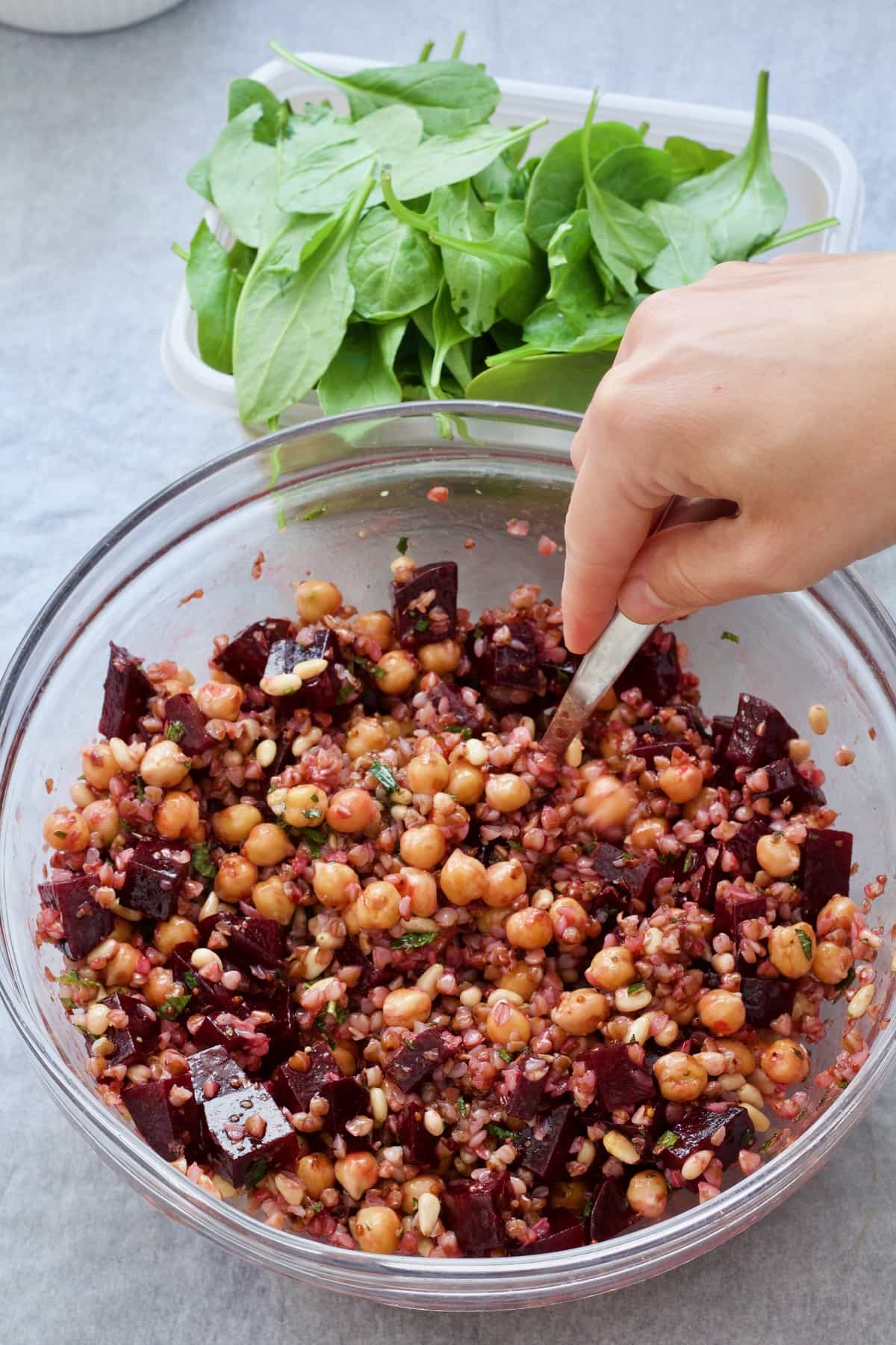 Hand mixing salad ingredients in a bowl.