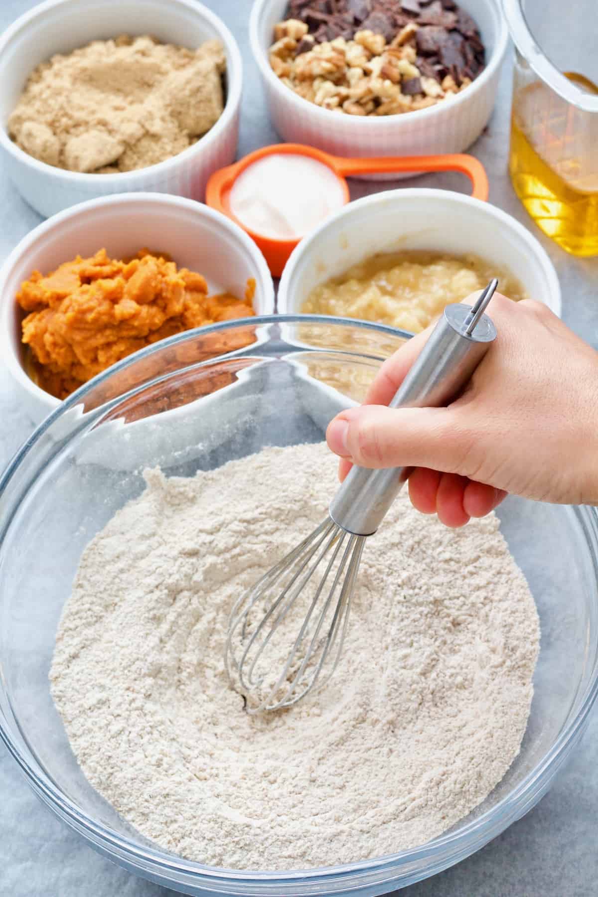 Hand whisking dry ingredients in a bowl.