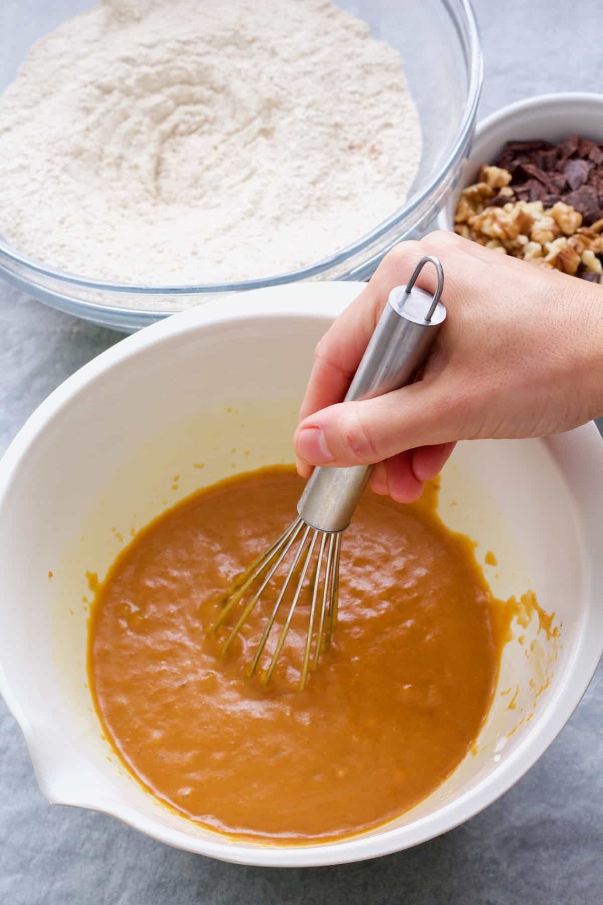 Hand whisking wet ingredients in a bowl.