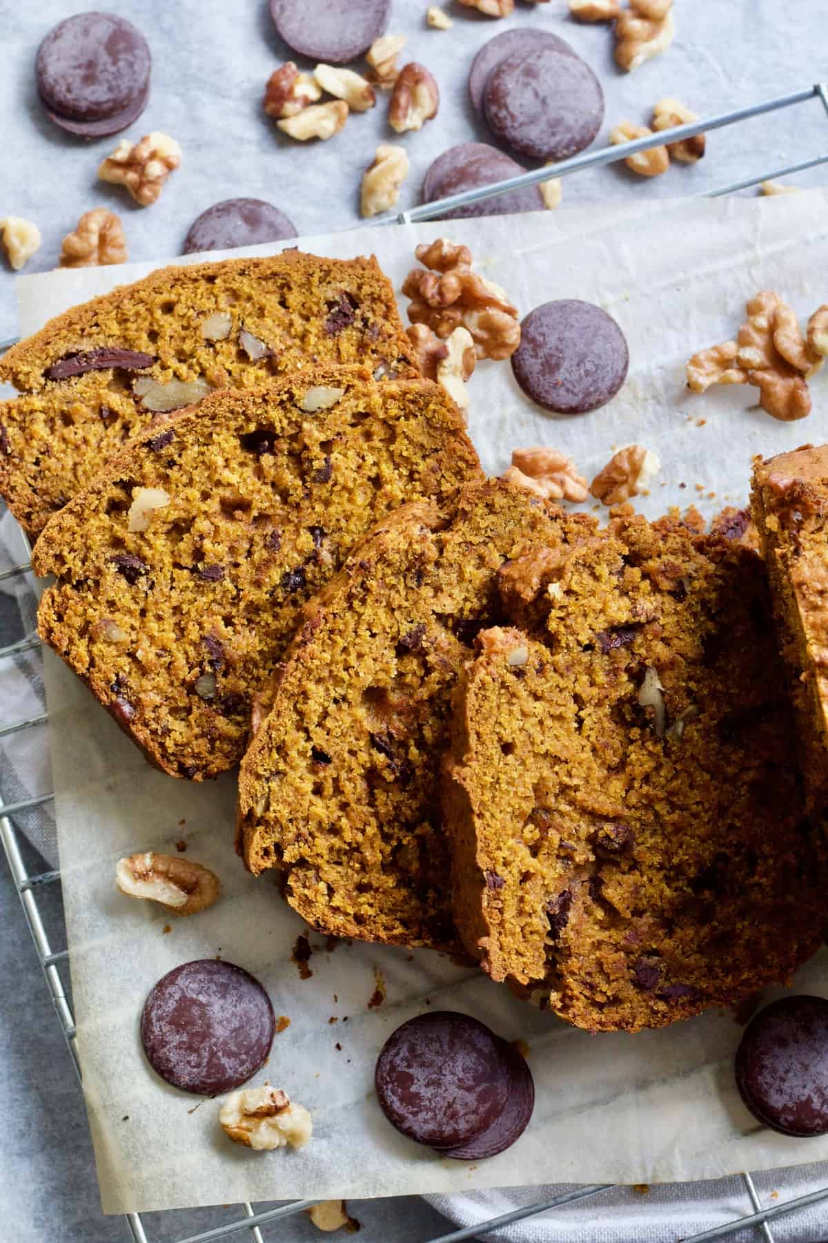 Four slices of pumpkin banana bread with chocolate & nuts around.