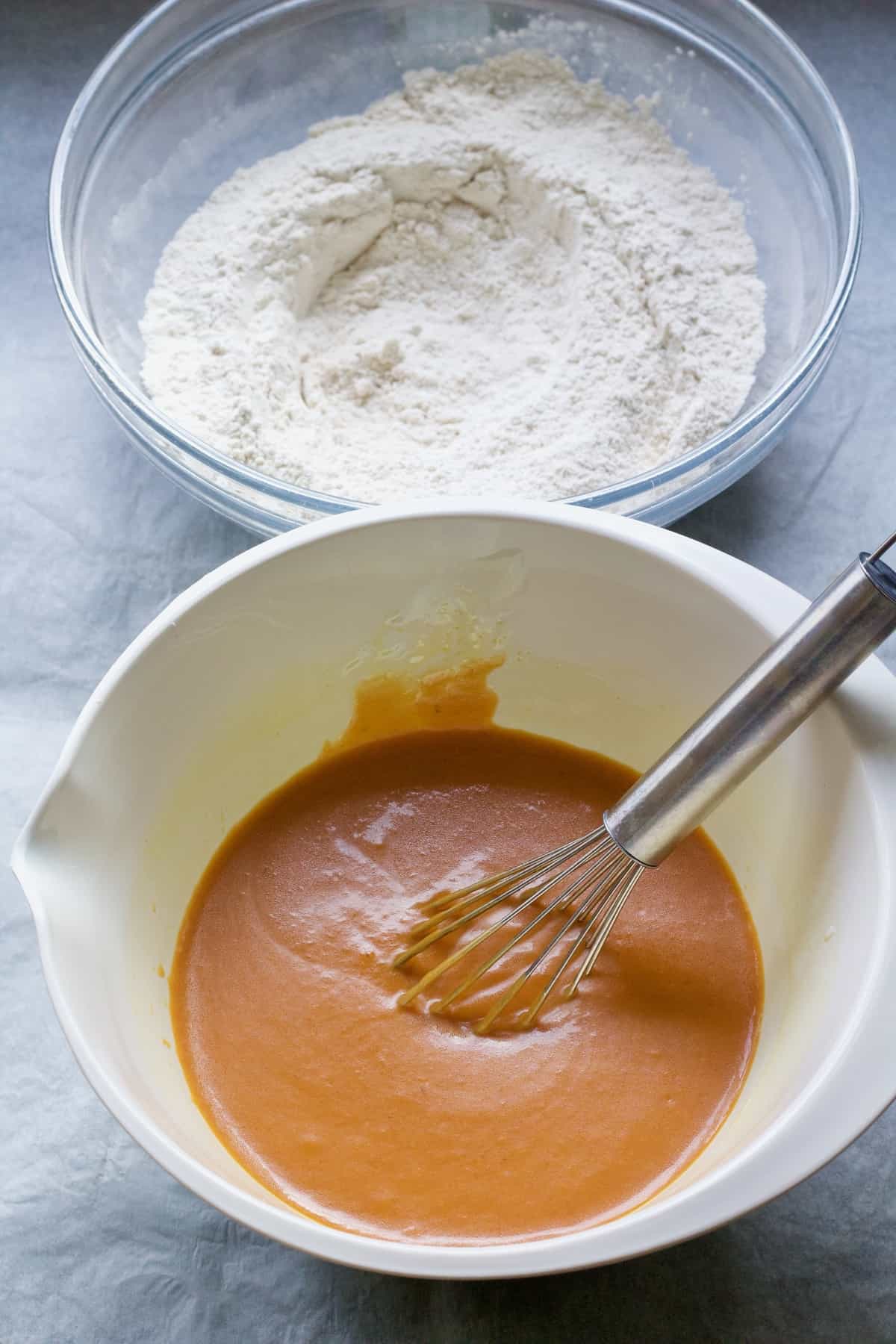 Mixed wet ingredients in a bowl with dry ingredients at the back.