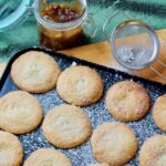 Mince pies in a tray, sieve and mincemeat jar.