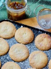 Mince pies in a tray, sieve and mincemeat jar.