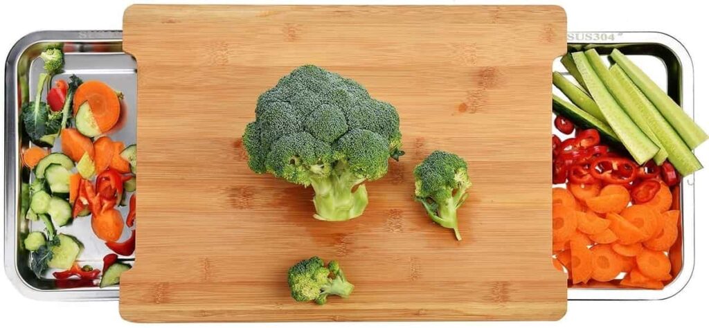 Chopping board with trays on both sides and vegetables.