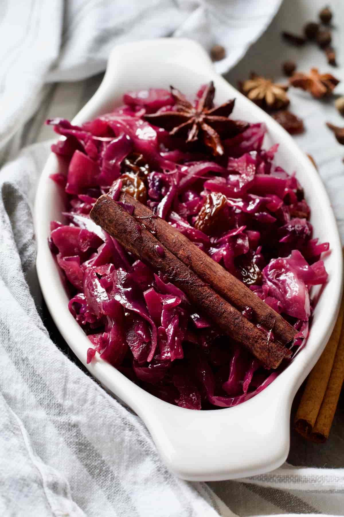 Red cabbage in a white oval dish with cinnamon stick.