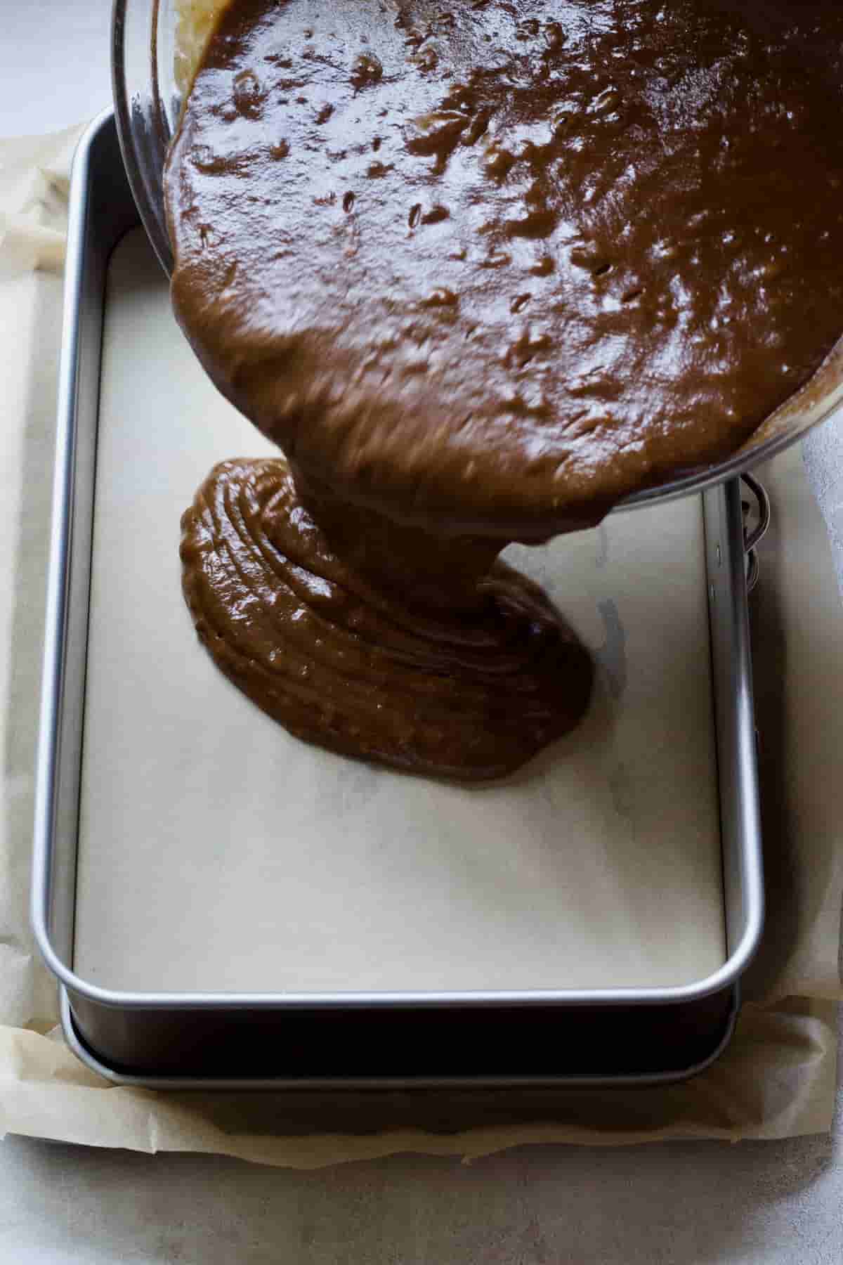 Cake batter being poured into baking tin.