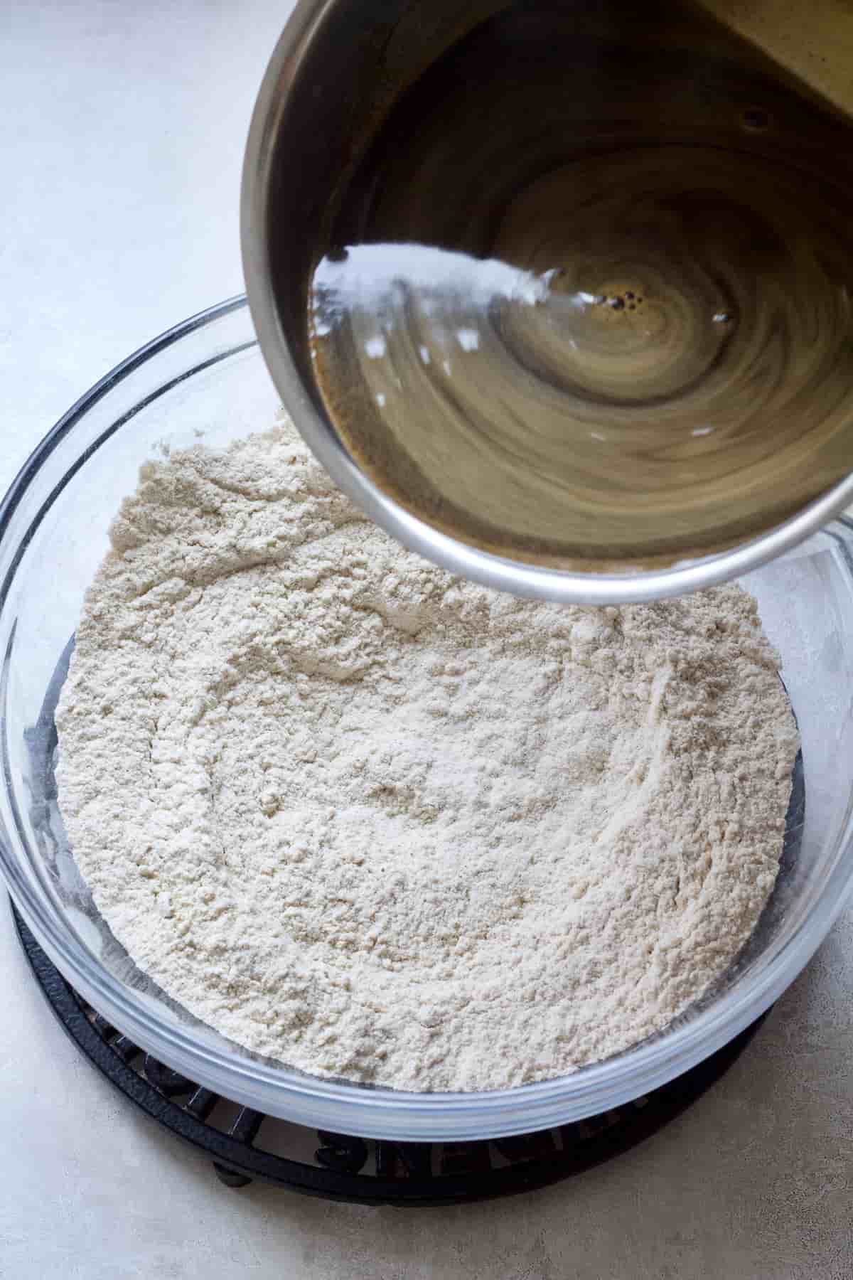 Wet mixture being poured into dry mix in a bowl.