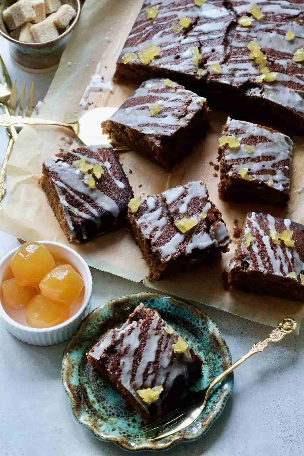 Gingerbread cake squares, one on a plate, stem ginger in a bowl.