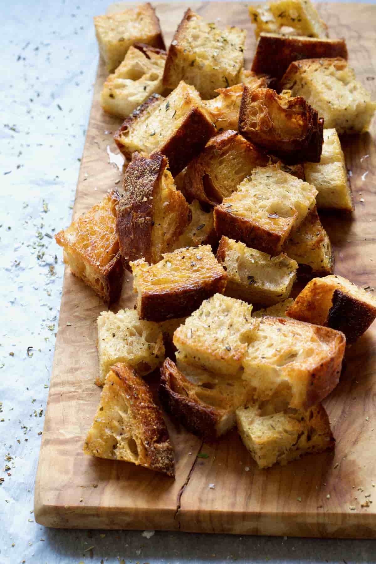 Homemade croutons piled up on a wooden board.