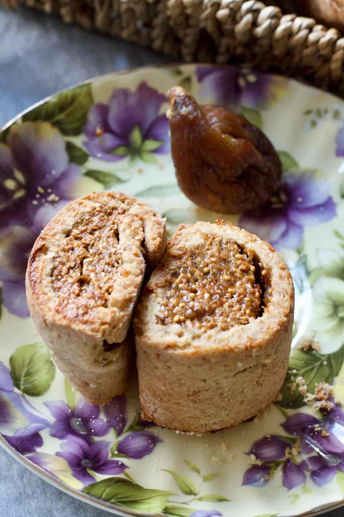 Two fig rolls on their sides on a plate with dried fig.