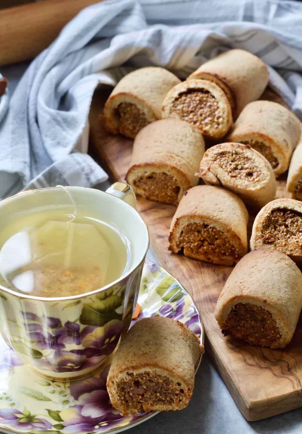 Fig roll on a saucer next to a cup of tea and more on a board.