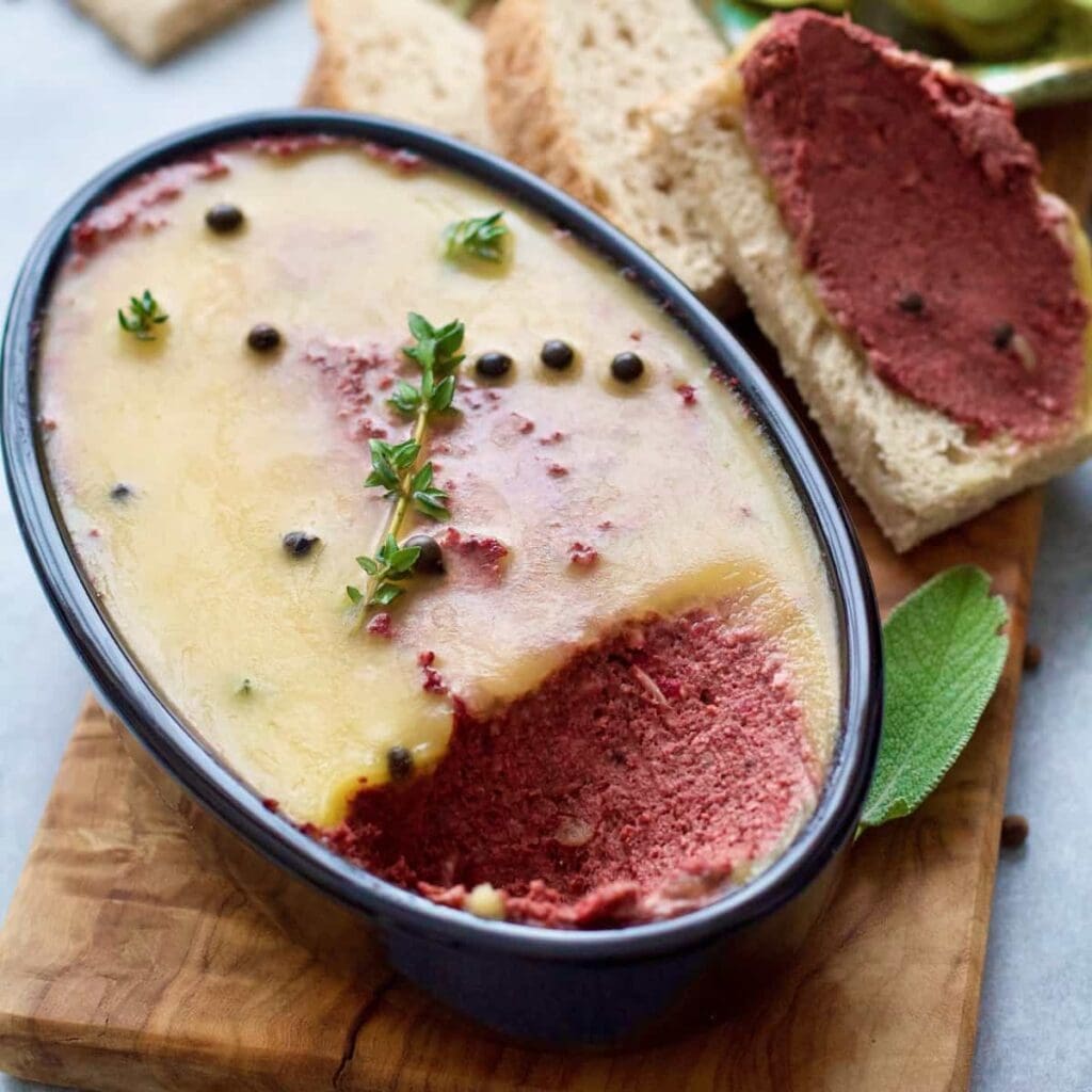 Mushroom and walnut pâté in an oval dish with thyme & peppercorns.