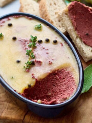 Mushroom and walnut pâté in an oval dish with thyme & peppercorns.