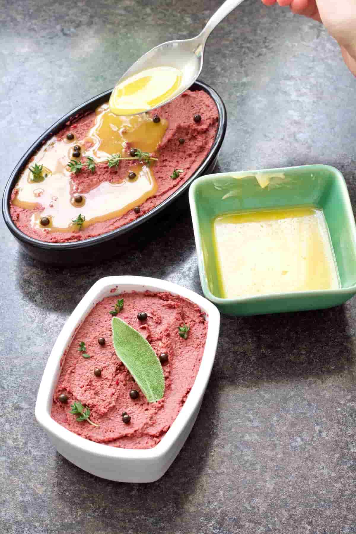 Ready pâté in two dishes with melted butter being poured over.