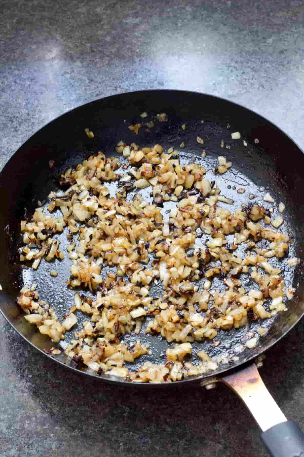 Fried pieces of onion in a frying pan.