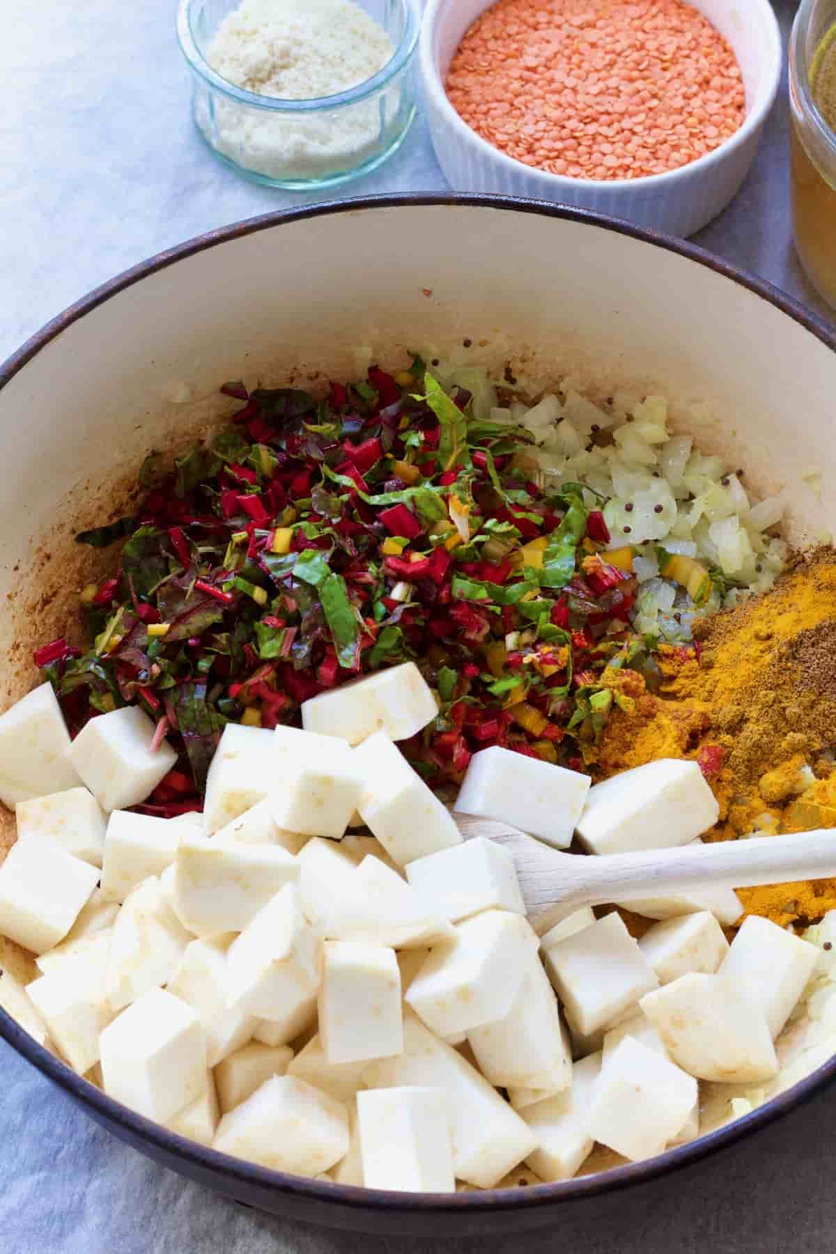 Pot with celeriac cubes, chard stalks, onion & spices.