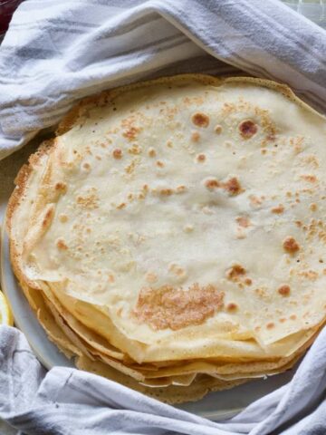 Vegan pancakes (crepes) piled up on a plate.