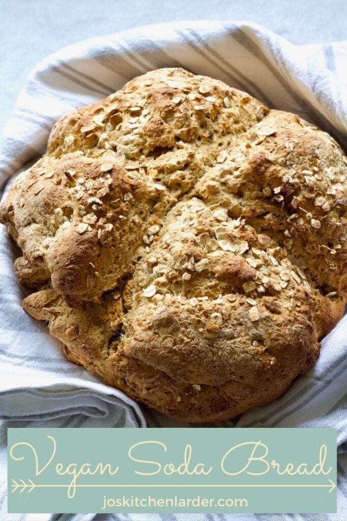 Baked loaf of bread wrapped in a kitchen towel.