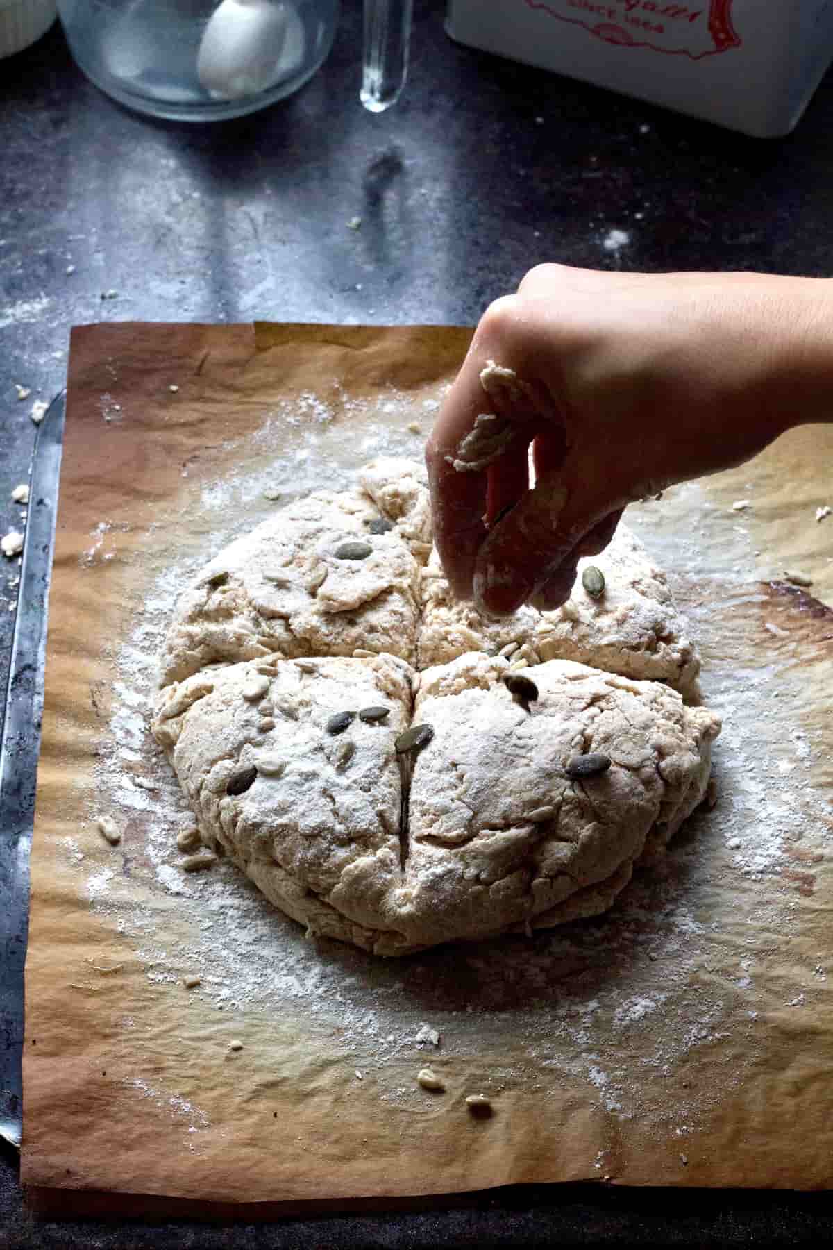 Hand sprinkling seeds over unbaked soda bread.