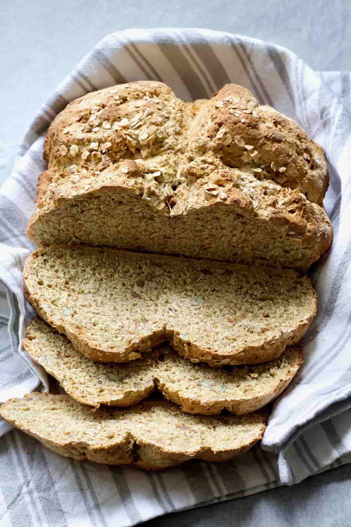 Loaf of vegan soda bread with few slices cut.