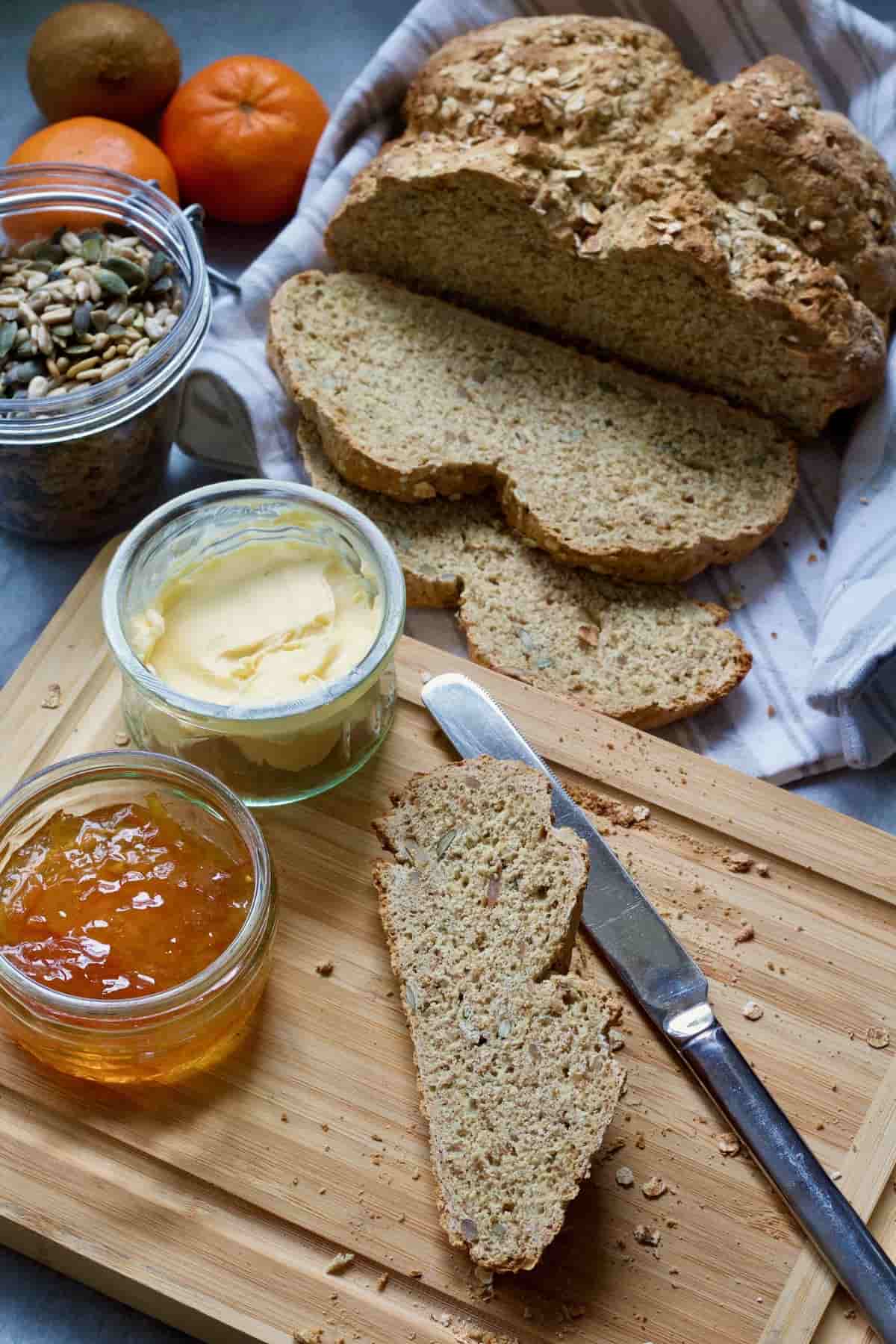 Slice of bread on a board, jar with butter & marmalade.