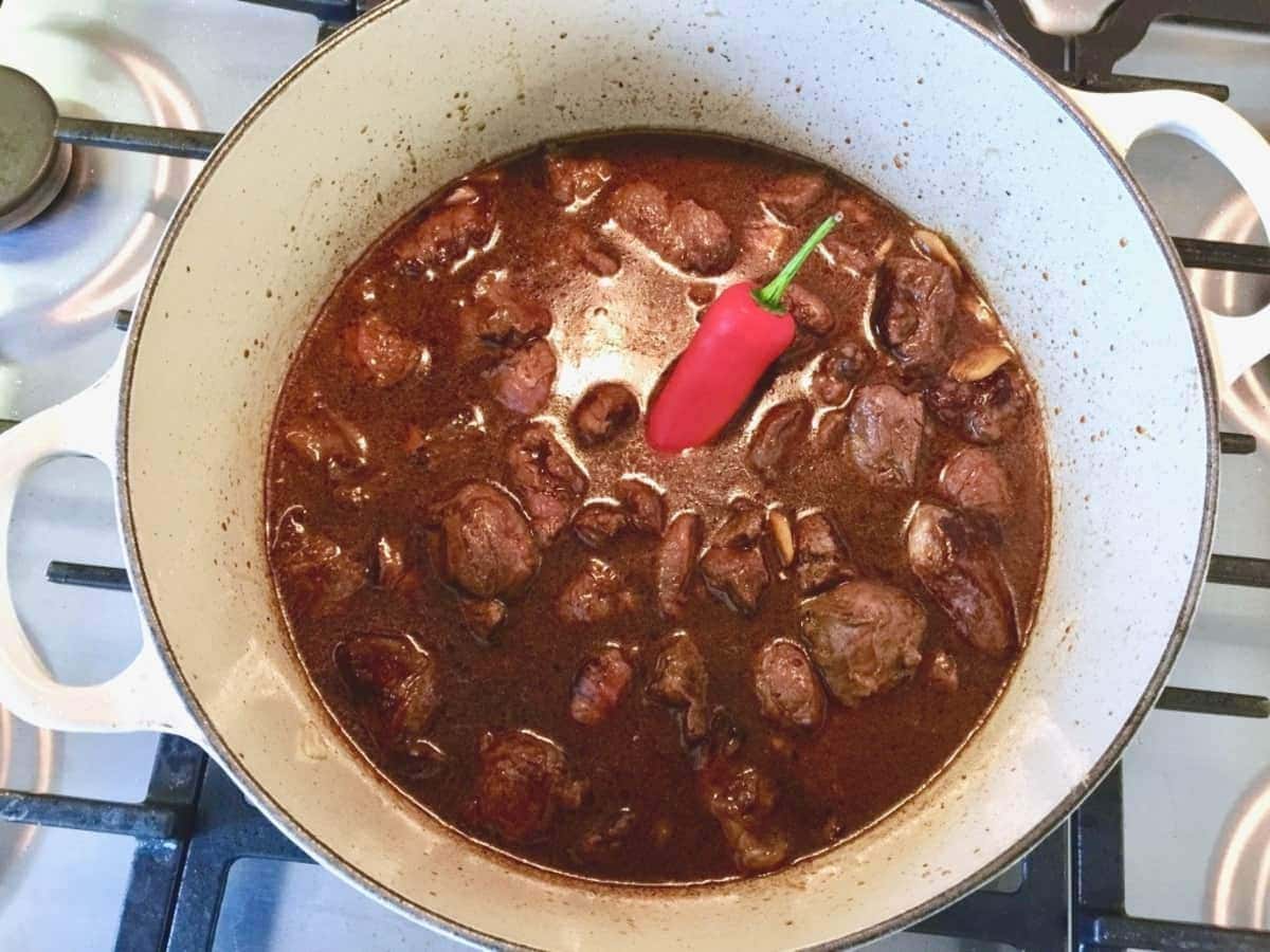 Beef stew in a pot with red chilli sticking out.