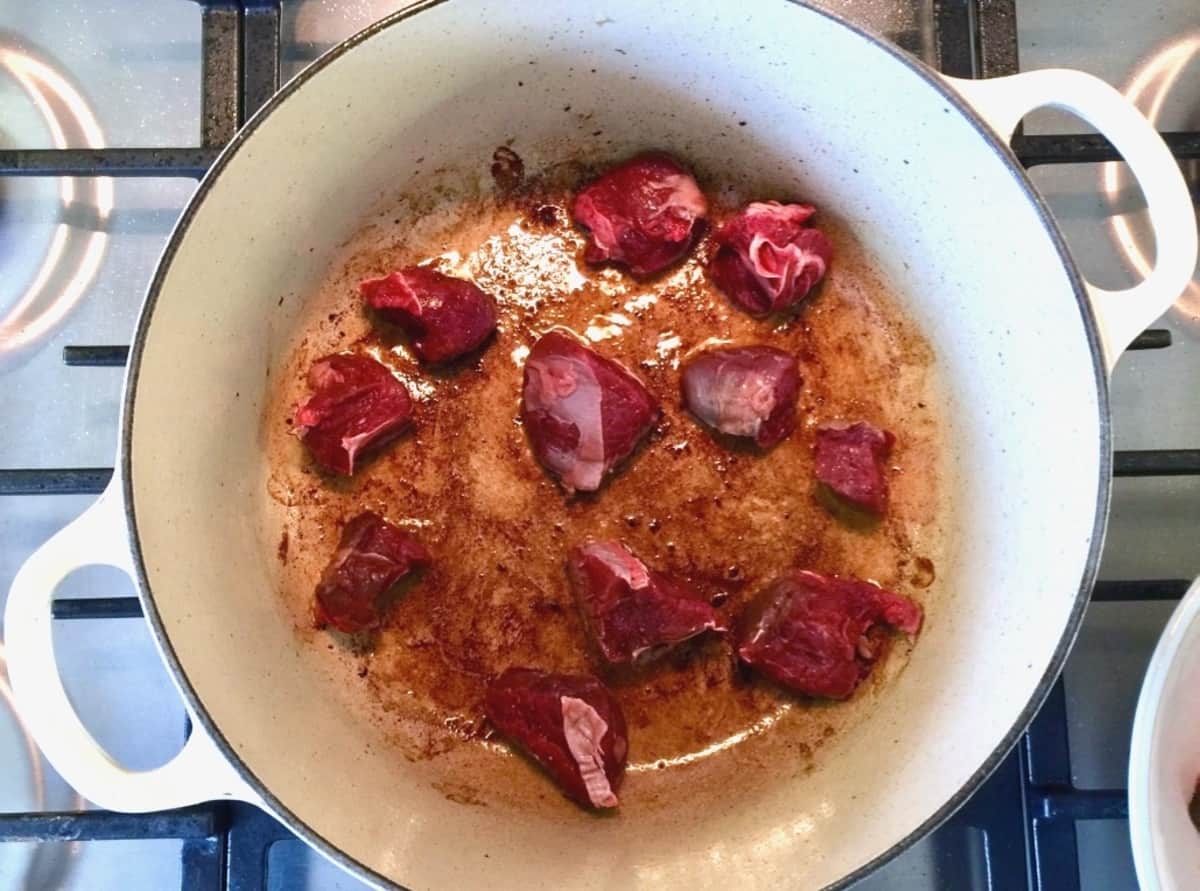 Beef pieces browning in a pan.