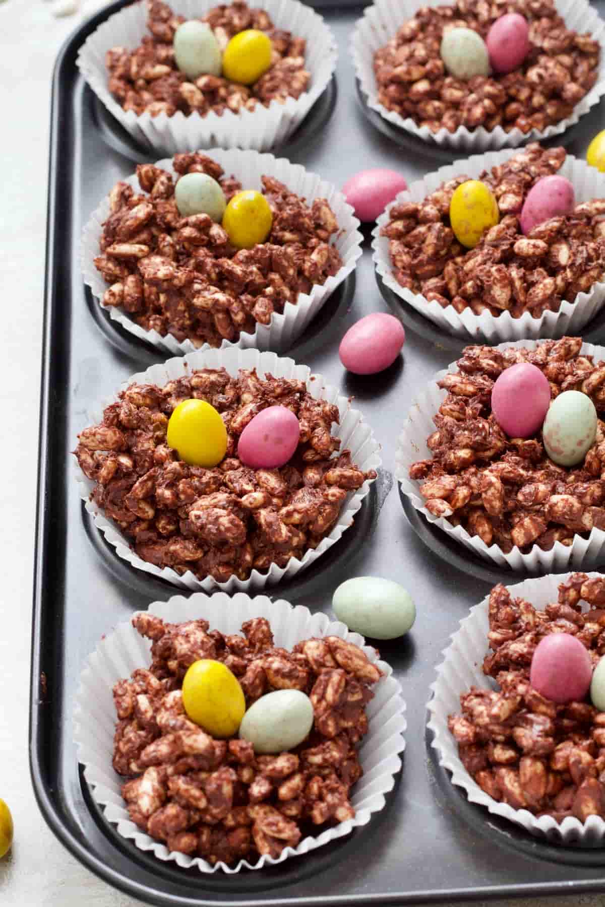 Two rows of chocolate nests with Mini Eggs on and around.