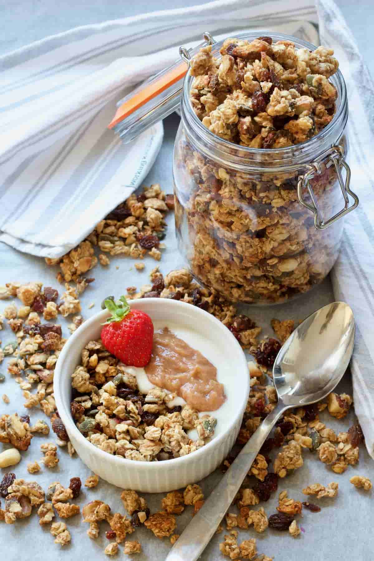 Jar with homemade granola and served portion in a bowl.