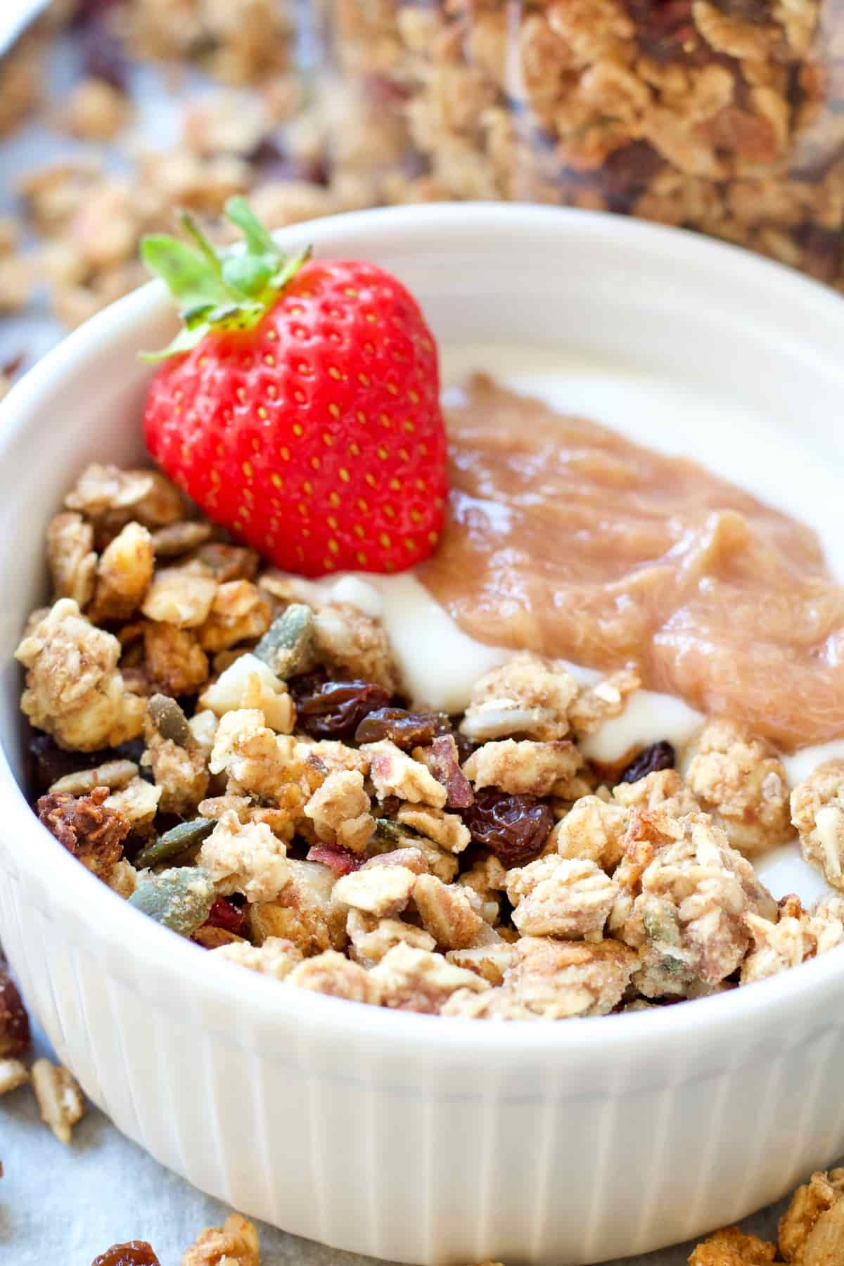 Bowl of granola with yogurt, rhubarb & a strawberry.