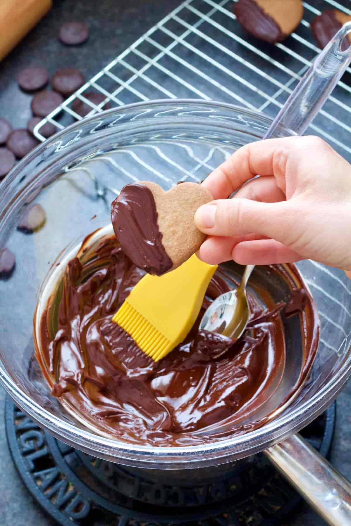 Hand holding a cookie half of which is covered in chocolate.