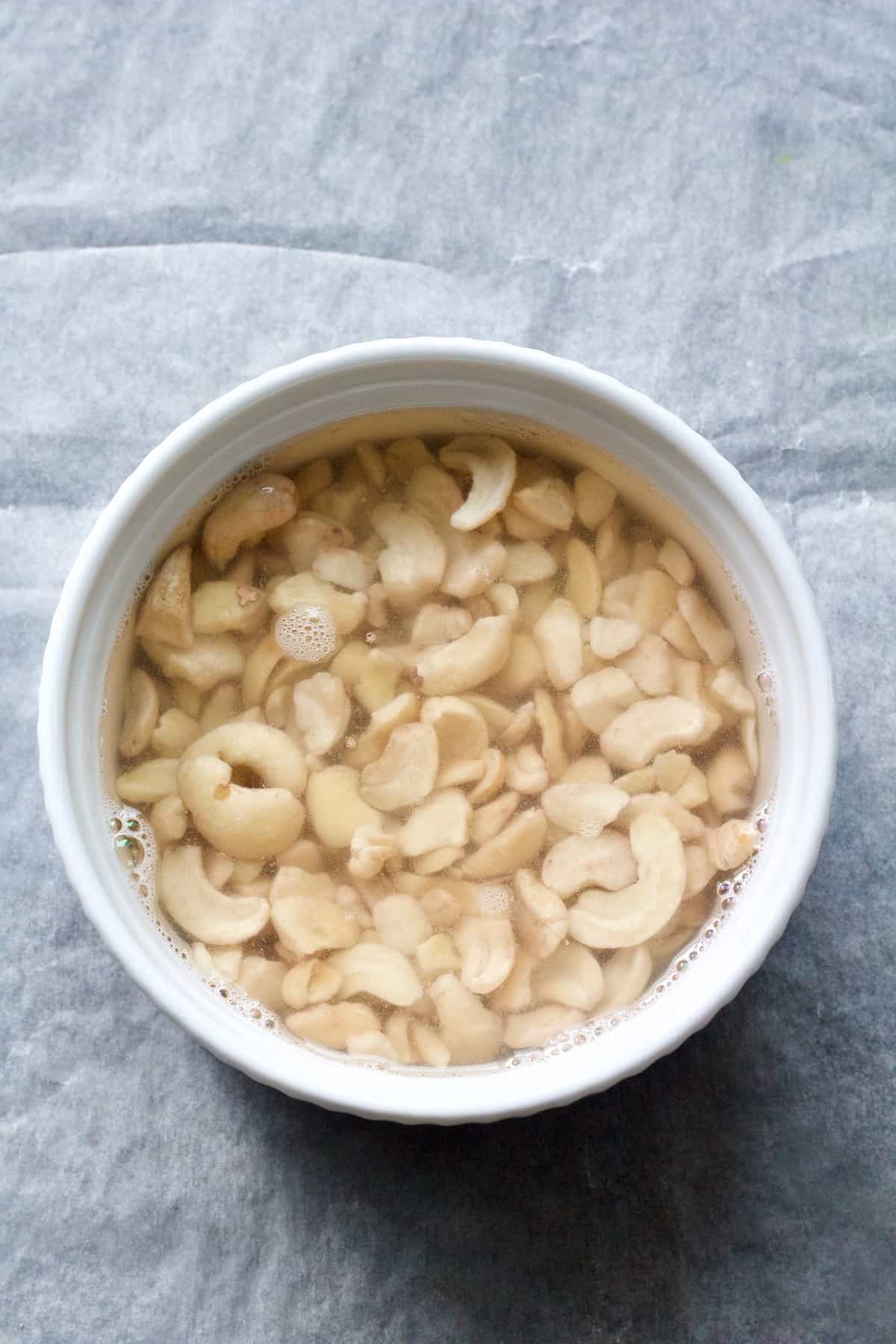 Raw cashew nuts soaking in a bowl of water.