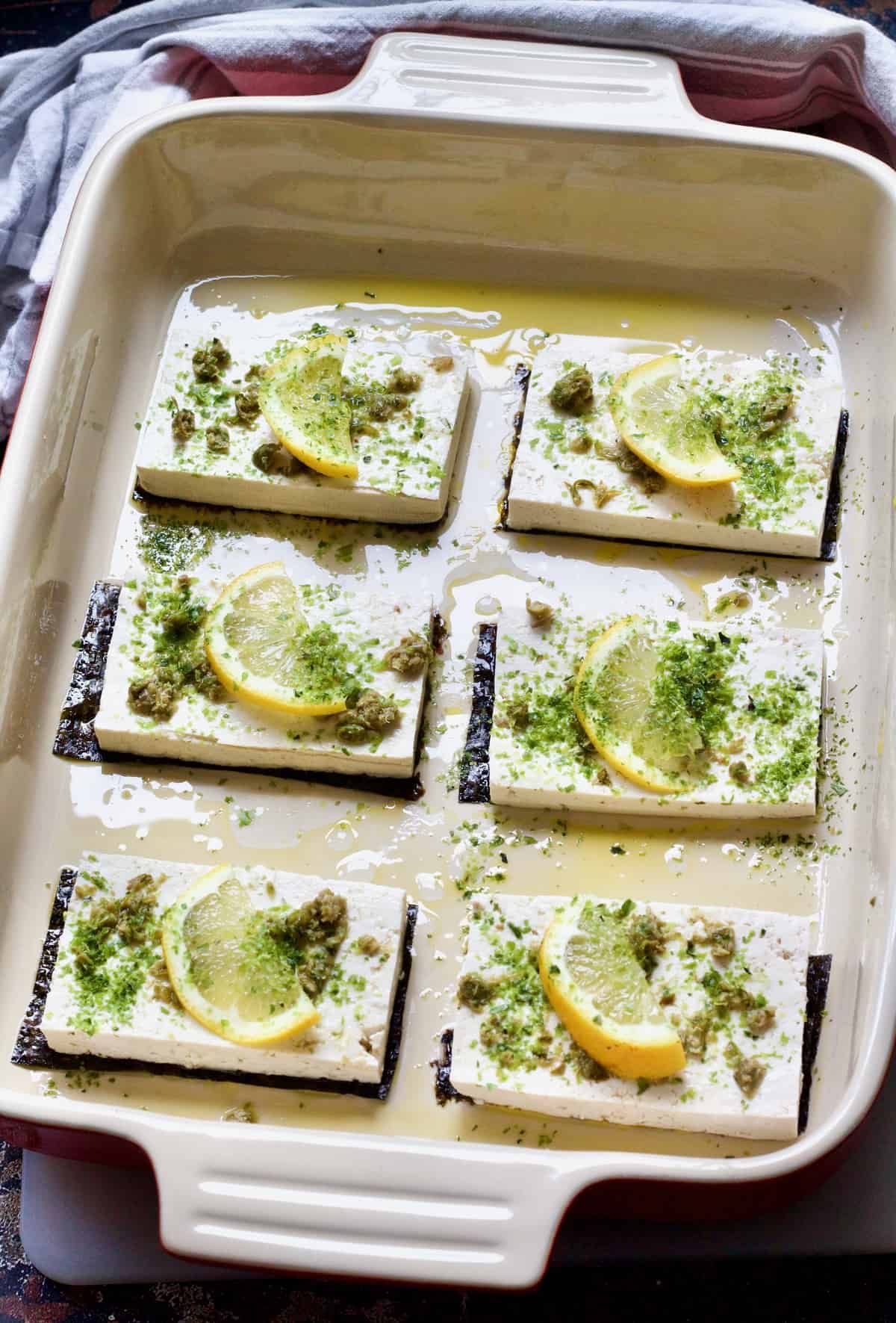 Unbaked tofu fish slices in a baking dish ready for the oven.