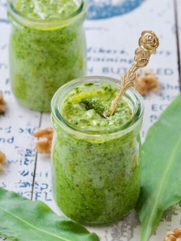 Jar full of pesto with golden spoon.