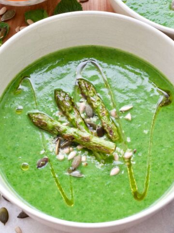 Bowl of asparagus soup with seeds and asparagus tips.