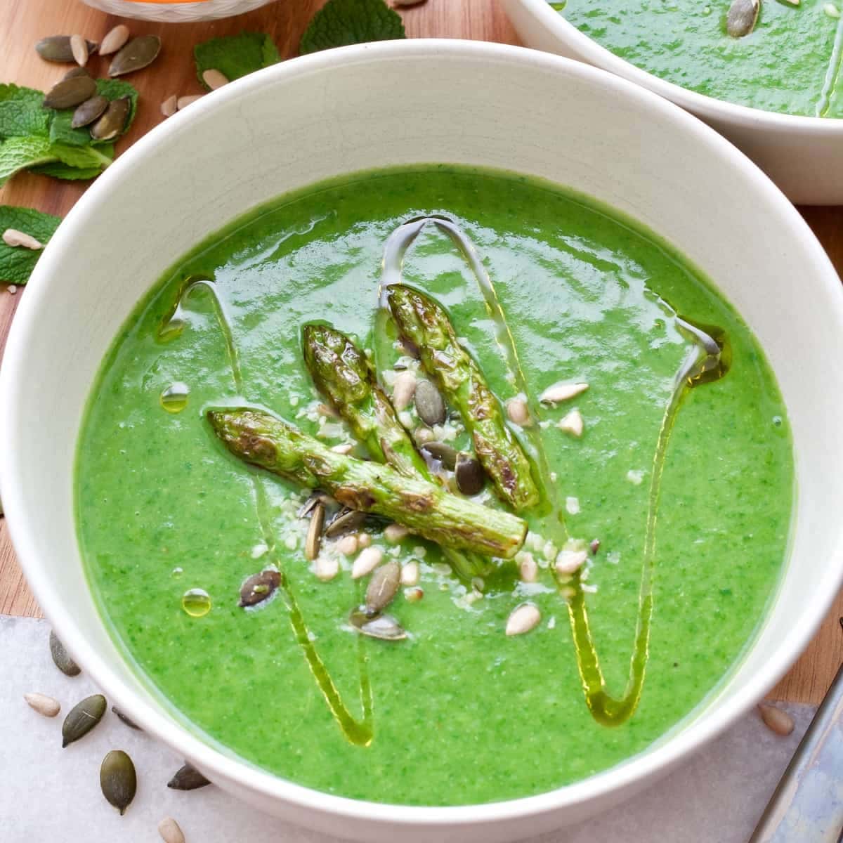 Bowl of asparagus soup with seeds and asparagus tips.