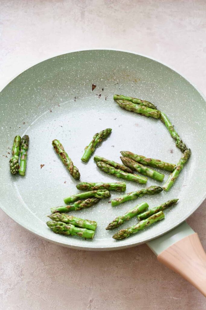 Fried asparagus tips in the pan.