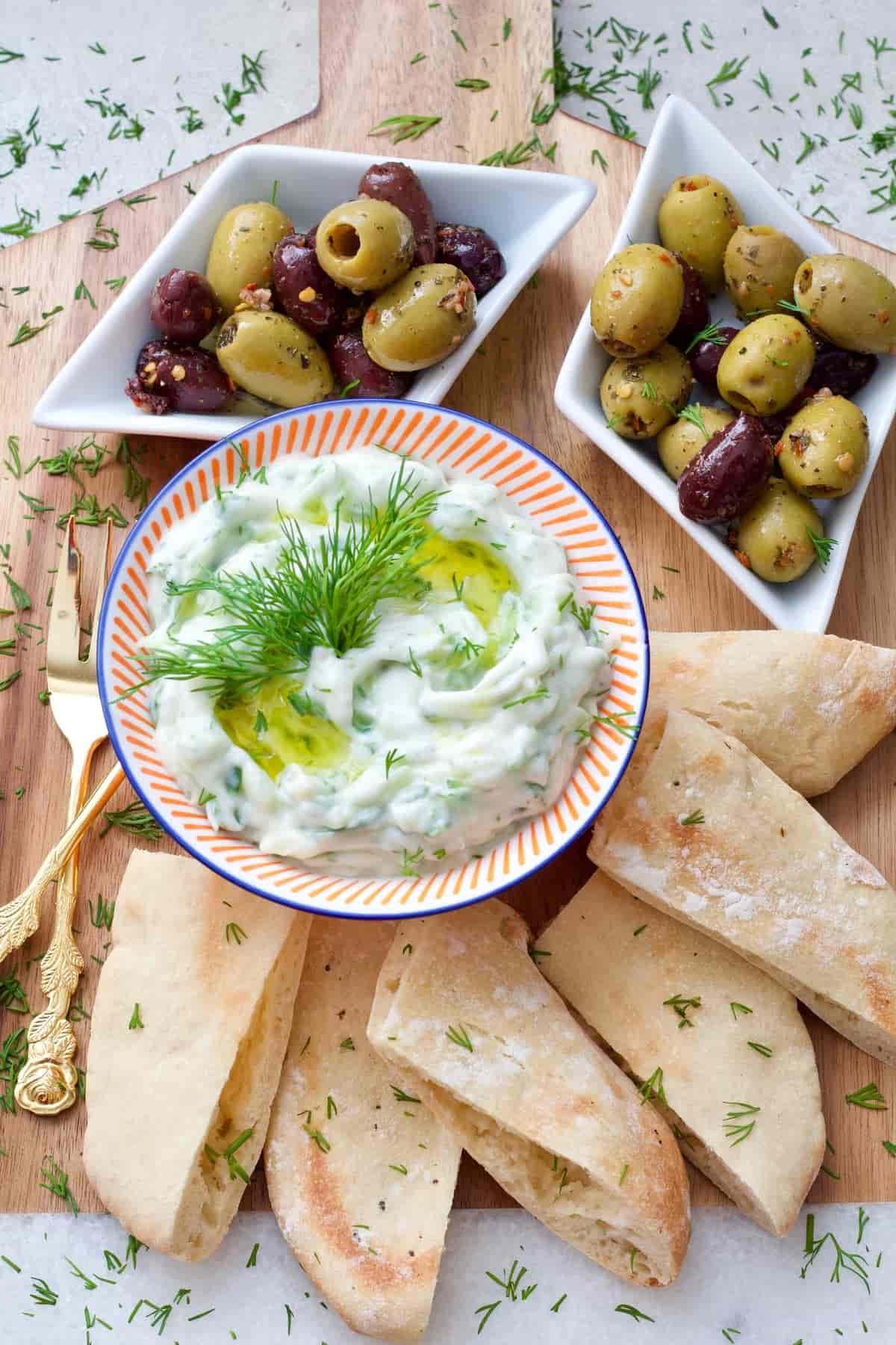 Dip in a bowl, olives & pita bread on a board.