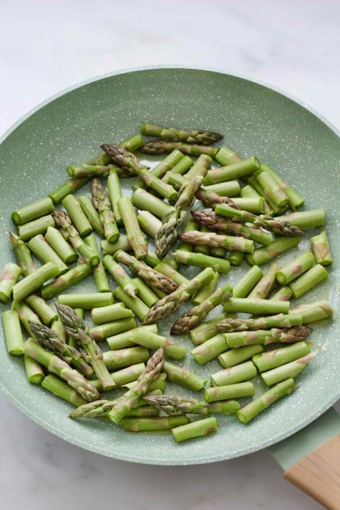 Fresh asparagus pieces in a pan before frying.