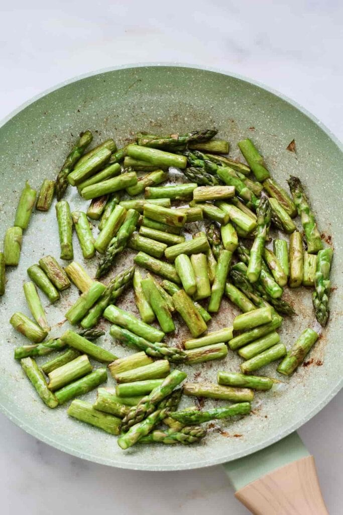 Fried asparagus pieces in a pan.