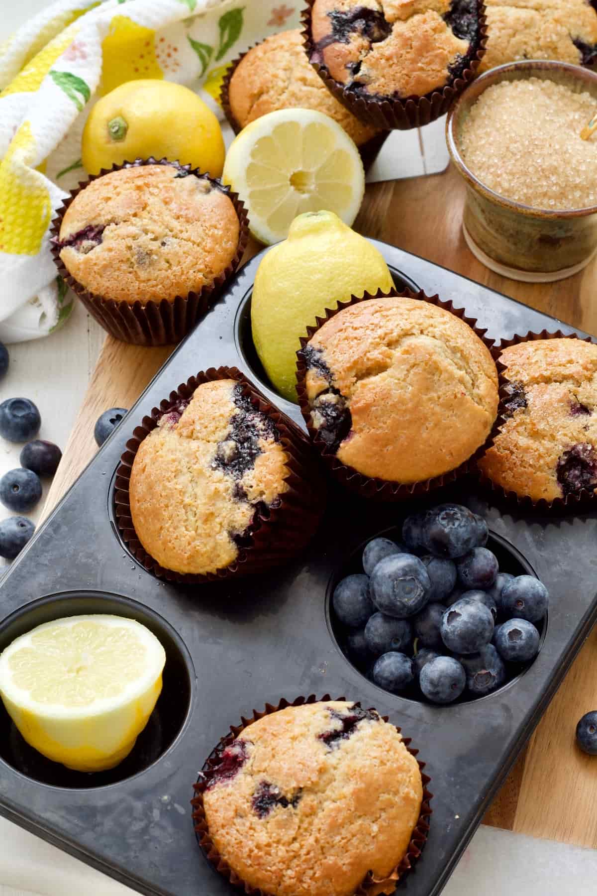 Muffin tin with muffins, lemons and blueberries in it.