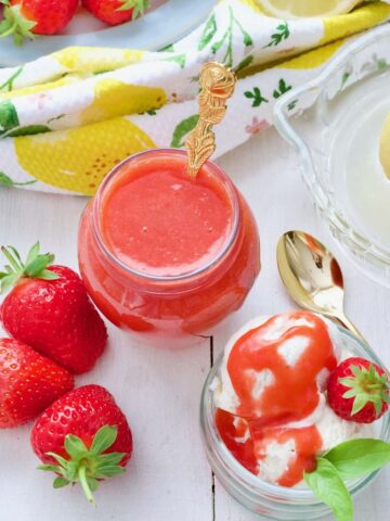 Strawberry coulis, bowl of ice cream, spoon, 3 fresh strawberries.