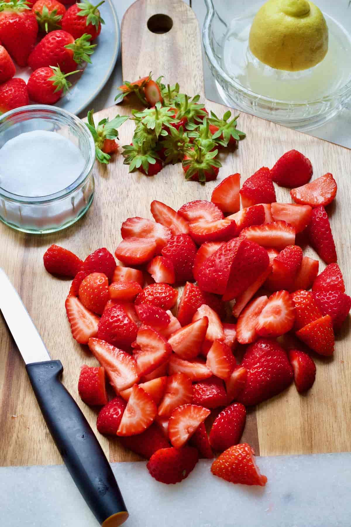 Hulled and chopped strawberries on a board.