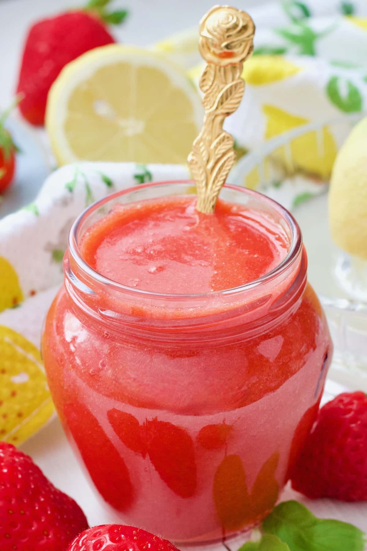 Strawberry coulis in a jar with a spoon.