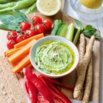 Bowl with broad bean dip, veg & crackers.