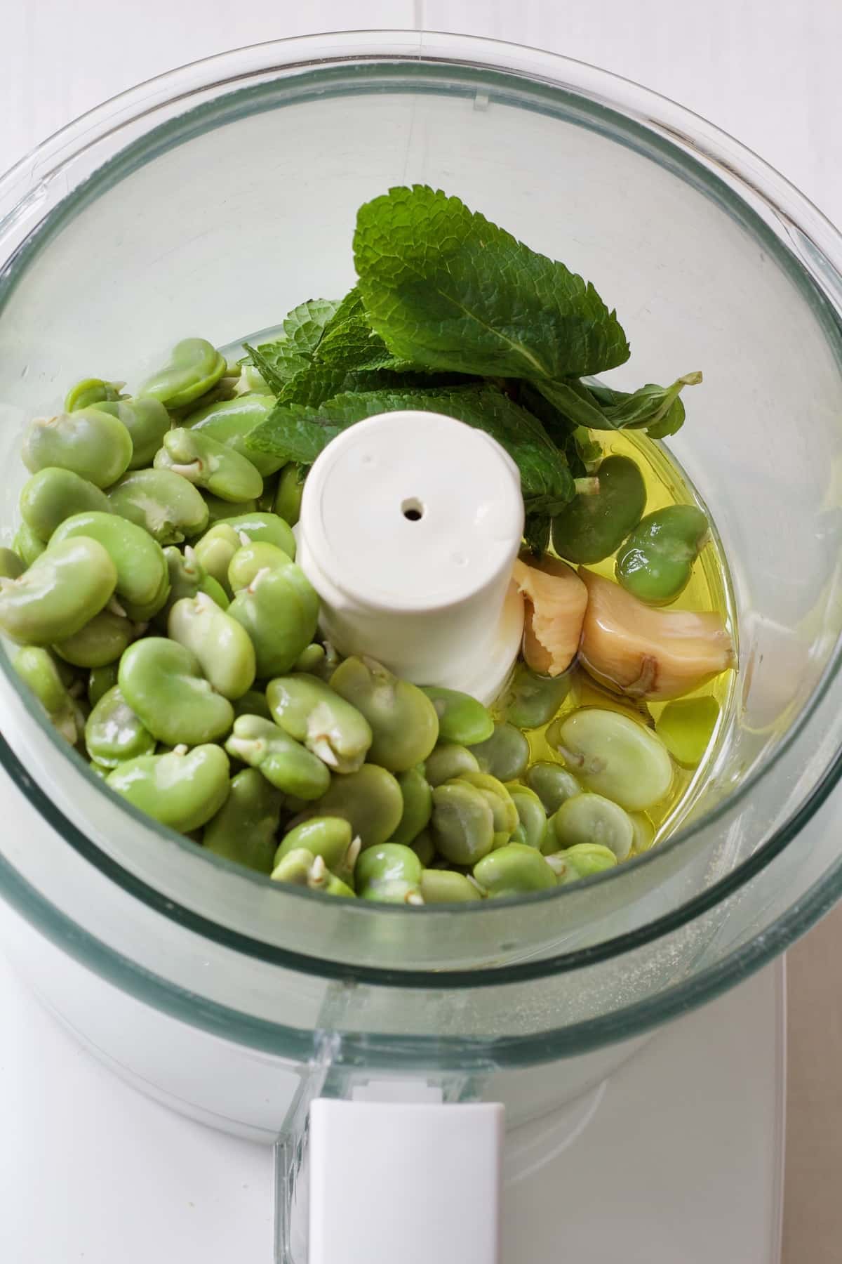 Broad beans, mint, garlic & oil in food processor.